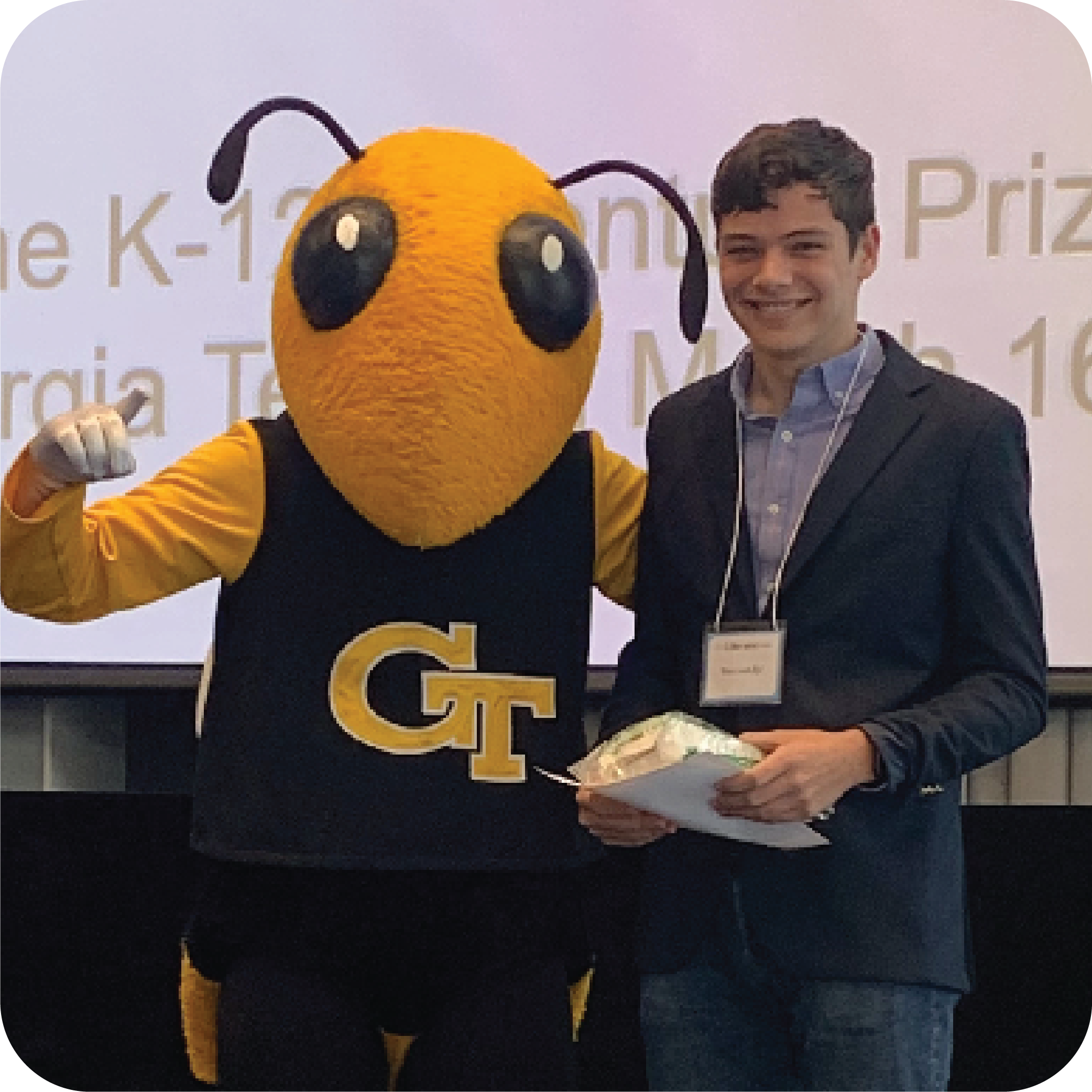 A smiling student holding prizes and standing next to Buzz (Georgia Tech's yellowjacket mascot).